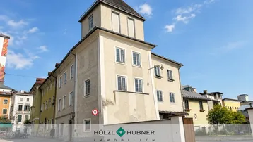 Historisches Gebäude mit markantem Turm und traditioneller Architektur in städtischer Umgebung.