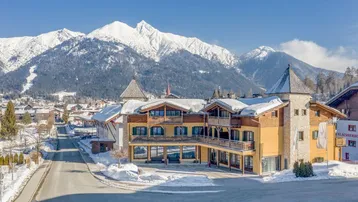 Gebäude im alpinen Stil mit schneebedeckten Dächern und majestätischer Bergkulisse im Winter.