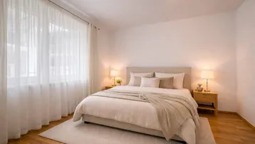 Gemütliches Schlafzimmer mit Doppelbett, Nachttischen und hellem Parkettboden.