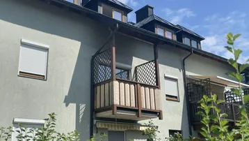 Balkon an der Fassade eines Mehrfamilienhauses mit Rollläden und Dachgauben.
