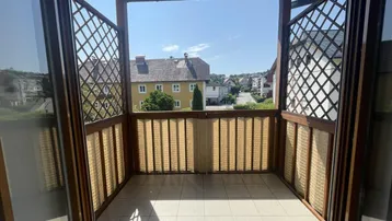 Überdachter Balkon mit Fliesenboden und Gitterverkleidung bietet Weitblick.