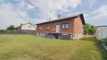 Einfamilienhaus im Rohbau mit großem Garten und Blick auf die ländliche Umgebung.