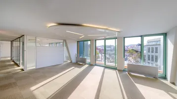 Geräumiges, helles Büro mit großen Fenstern, Teppichboden und Blick auf die Stadt.