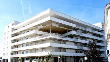 Modernes Apartmentgebäude mit mehreren Balkonen unter blauem Himmel und klarer Architektur.