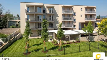 Modernes Mehrfamilienhaus mit mehreren Balkonen und gepflegter Grünfläche im Außenbereich.