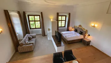 Geräumiges Schlafzimmer mit elegantem Bett, Sitzbereich und hohen Decken, durchflutet von natürlichem Licht.