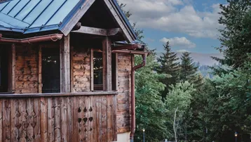 Charmantes Holzhaus mit traditionellem Balkon und malerischem Bergblick inmitten grüner Natur.