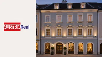 Elegante Gebäudefassade mit klassischer Architektur, beleuchteten Fenstern und dekorativen Elementen am Abend.
