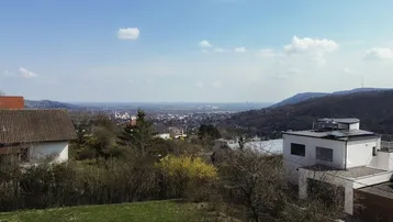 Weitläufiger Blick über die Landschaft und eine Stadt in der Ferne unter blauem Himmel.