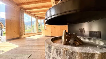 Rustikales Wohnzimmer mit Holzboden, Holzwänden und einem beeindruckenden zentralen Kamin.