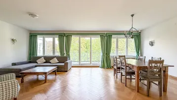 Geräumiger Wohn-Essbereich mit Fischgrätparkett, großen Fenstern und Zugang zum Balkon.