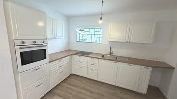 Moderne Küche mit weißen Schränken, Holzarbeitsplatte, Einbauherd und Induktionskochfeld.