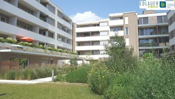 Moderne Wohngebäude mit Balkonen und begrüntem Innenhof, der zum Verweilen einlädt.