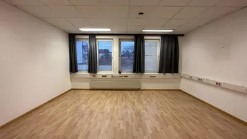 Geräumiger, leerer Büroraum mit hellem Laminatboden und mehreren Fenstern, bereit zur individuellen Gestaltung.