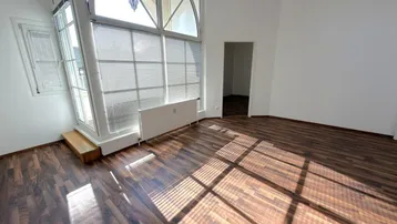 Heller Raum mit großen Fenstern, Laminatboden und viel natürlichem Licht, ideal als Wohnzimmer.