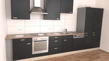 Moderne Küche mit dunklen Schränken, Holzarbeitsplatte und integrierten Edelstahlgeräten, bereit zur Nutzung.