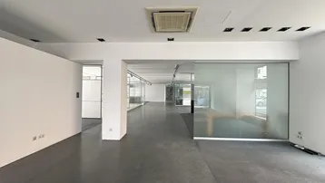 Geräumiger, heller Büroraum mit modernen Glasabtrennungen und dunklem Bodenbelag, bereit zur individuellen Gestaltung.