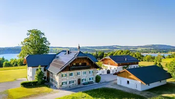 Großzügiges Anwesen mit mehreren Gebäuden, Photovoltaikanlage und Seeblick in ländlicher Umgebung.