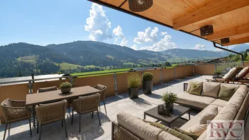 Geräumige Sonnenterrasse mit bequemen Loungemöbeln, Esstisch und atemberaubendem Bergblick.