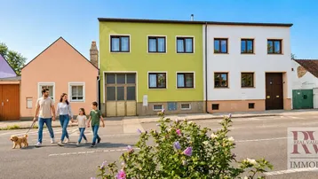 Mehrere Wohnhäuser in einer ruhigen Wohngegend mit einer Familie, die auf der Straße spaziert.