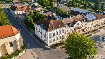 Luftaufnahme einer charmanten Kleinstadt mit historischen Gebäuden, grünen Hügeln und Solaranlagen auf Dächern.
