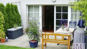 Gepflasterte Terrasse mit Gartenmöbeln und direktem Zugang zum Wohnbereich und Garten.