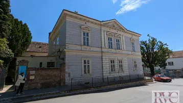 Historisches Gebäude mit klassischer Fassade an einer Straßenecke unter blauem Himmel.