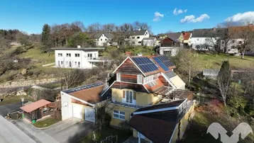 Luftaufnahme des Hauses mit Solaranlage auf dem Dach und umliegender grüner Landschaft.