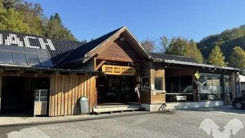 Rustikales Holzgebäude mit dem Schild "Boot Hill Saloon" und einem großen Parkplatz davor unter blauem Himmel.
