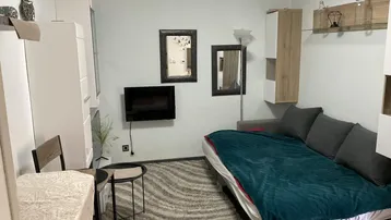 Gemütlicher Wohnbereich mit Schlafsofa, kleinem Esstisch und moderner Dekoration.