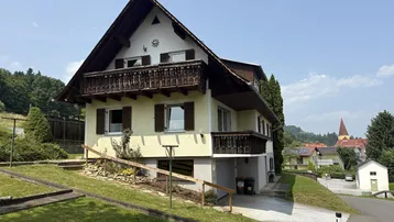 Freistehendes Haus mit mehreren Balkonen und Blick auf die umliegende Landschaft und ein Dorf.