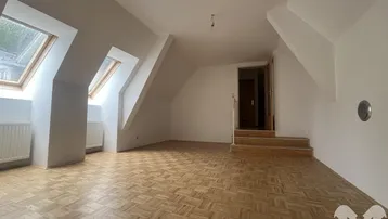 Helles Dachgeschosszimmer mit Parkettboden, Dachschrägen und mehreren Dachfenstern.