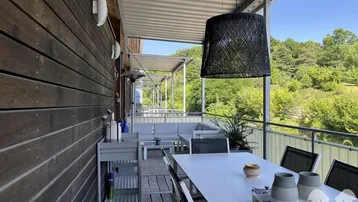 Geräumiger Balkon mit Essbereich und Lounge-Möbeln, umgeben von viel Grün.