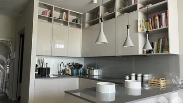 Moderne Küche mit glänzenden Fronten, integrierten Regalen und stilvollen Pendelleuchten.