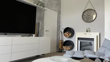 Wohnzimmer mit modernem Kamin, Fernseher und dekorativer Wandgestaltung.