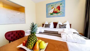 Gemütliches Schlafzimmer mit Doppelbett, frischen Früchten auf dem Tisch und einem farbenfrohen Kunstwerk an der Wand.