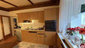 Gemütliche Einbauküche mit Holzfronten, integrierten Geräten und Deckenbalken.