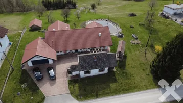 Luftaufnahme des Anwesens mit Wohnhaus, Garage, Teich und weitläufigem Garten in ländlicher Umgebung.