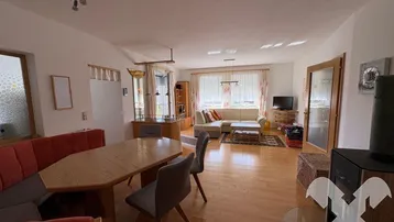 Geräumiger Wohn-Essbereich mit Holzboden, gemütlicher Sitzecke und Kaminofen.