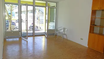 Geräumiger Wohnbereich mit viel Tageslicht, großen Fenstern und Zugang zum Außenbereich.