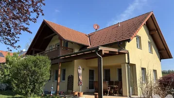 Geräumige Terrasse mit Gartenmöbeln unter einer Pergola, umgeben von einem gepflegten Garten.