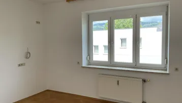 Helles Zimmer mit Parkettboden und weitem Blick auf die umliegende Landschaft.