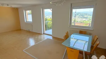 Heller Wohn-Essbereich mit Zugang zum Balkon und weitem Blick über die Landschaft.