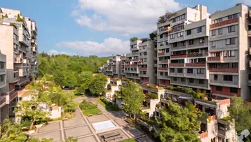 Weitläufige Wohnanlage mit viel Grünfläche und modernen Gebäuden unter blauem Himmel.