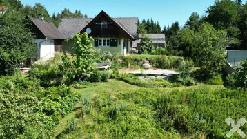 Ansicht des Hauses von der Wiese aus, umgeben von üppiger Vegetation und Bäumen.