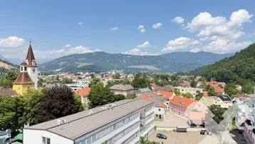 Panoramablick über eine charmante Stadt mit historischen Gebäuden und majestätischen Bergen im Hintergrund.