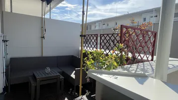 Gemütliche Terrasse mit Rattanmöbeln und Holzboden, ideal für entspannte Stunden im Freien.