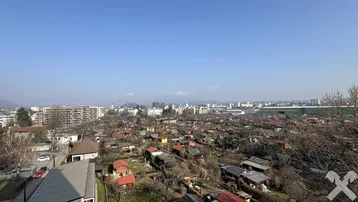 Weitläufiger Blick über eine städtische Siedlung mit vielen Häusern und Bergen im Hintergrund an einem sonnigen Tag.