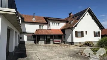 Ansicht des Haupthauses mit weißer Fassade, roten Dachziegeln und Solarpaneelen.