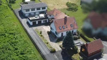 Luftaufnahme des Anwesens mit mehreren Gebäuden, Terrasse und umliegenden Feldern.